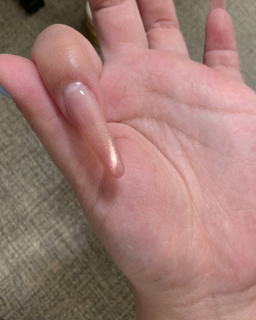 Nahaufnahme eines magnetischen Nagelwerkzeugs, das über einem mit Cat-Eye-Gel beschichteten Nagel gehalten wird, wodurch die Partikel eine Linie bilden.
