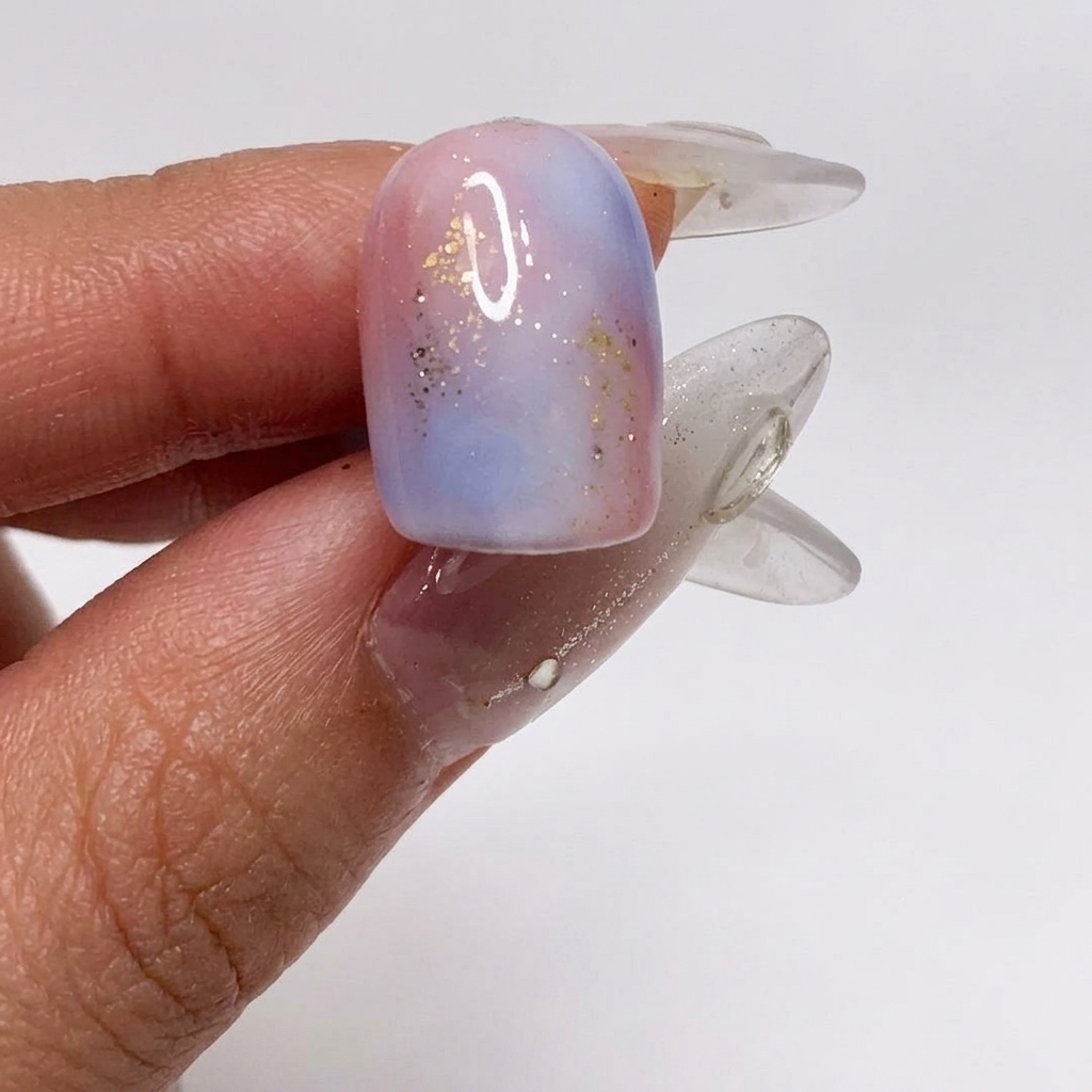 Ein Pinsel trägt ein mattes Top Coat über den strukturierten, glitzernden Nagel auf.