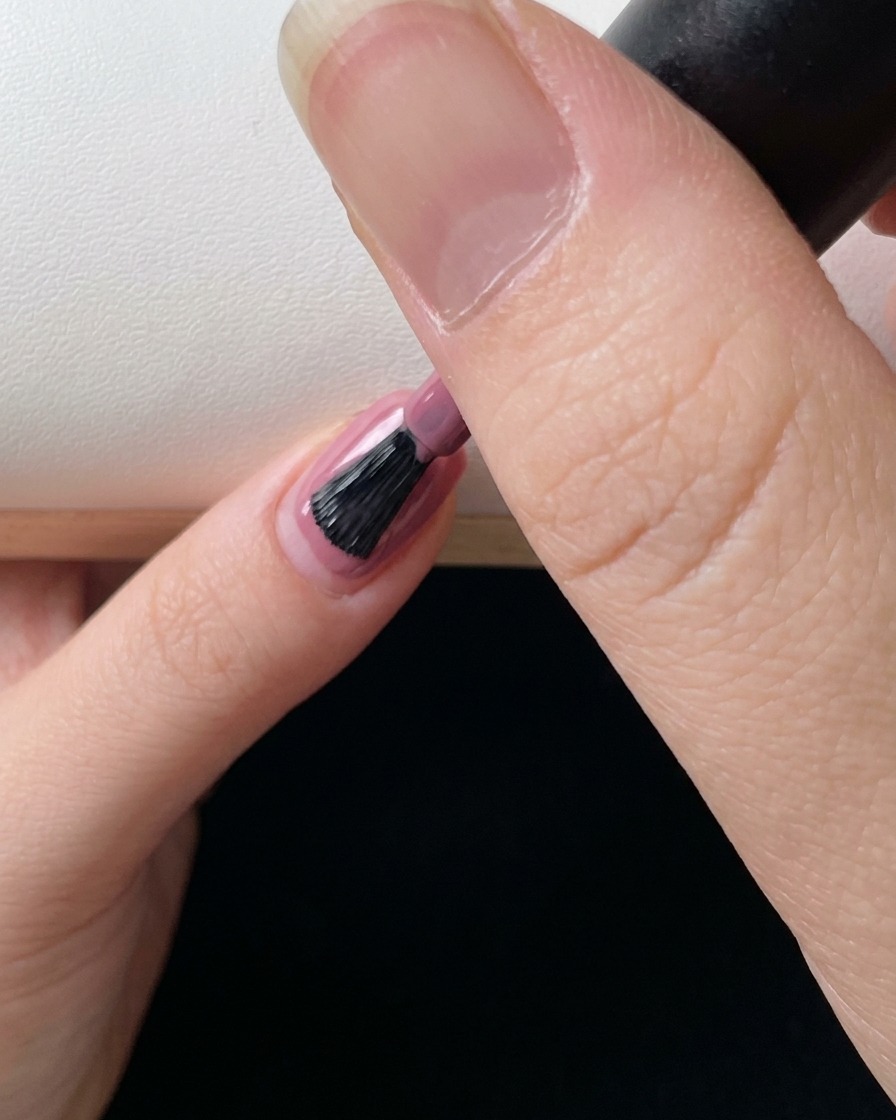 Nahaufnahme eines Pinsels, der eine letzte Schicht rosa Farbgel aufträgt, um den Gradienten-Effekt zu perfektionieren.