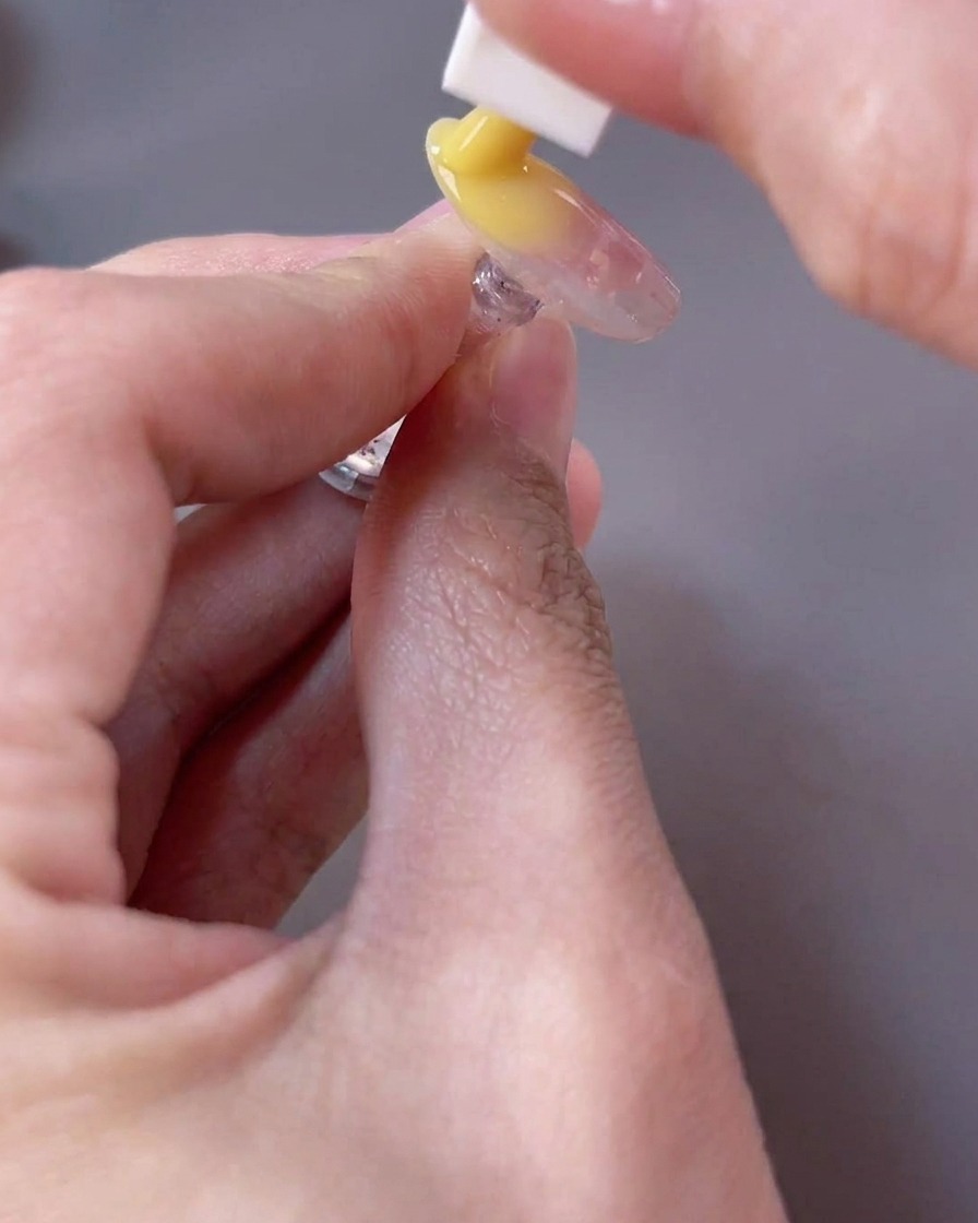 Ein Schwämmchen tupft ein leuchtend gelbes Gel auf die freie Nagelkante, um einen Ombré-Effekt zu erzielen.