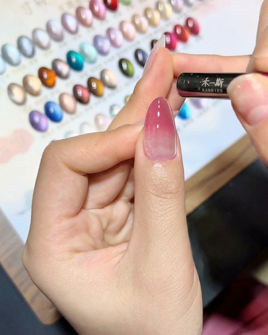 Ein Magnetwerkzeug wird dicht über einen mit Cat-Eye-Gel bestrichenen Nagel gehalten, um eine Schimmerlinie zu erzeugen.