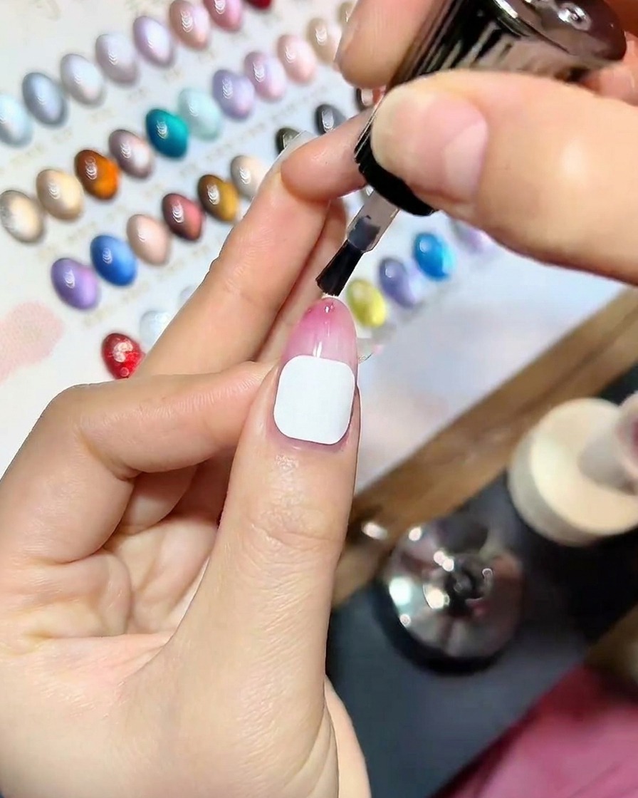 Nahaufnahme einer Hand mit frisch aufgetragenem Top Coat in einer professionellen UV-Lampe, blaues Licht beleuchtet die Nägel.