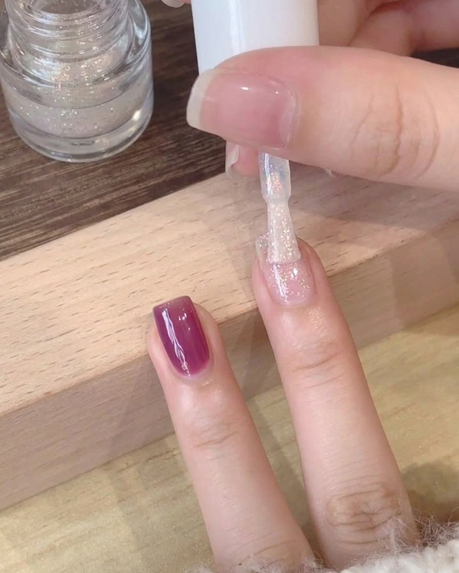 Nahaufnahme eines schimmernden, polarisierten Top Coats, der über einer tiefvioletten Gelbasis aufgetragen wird.