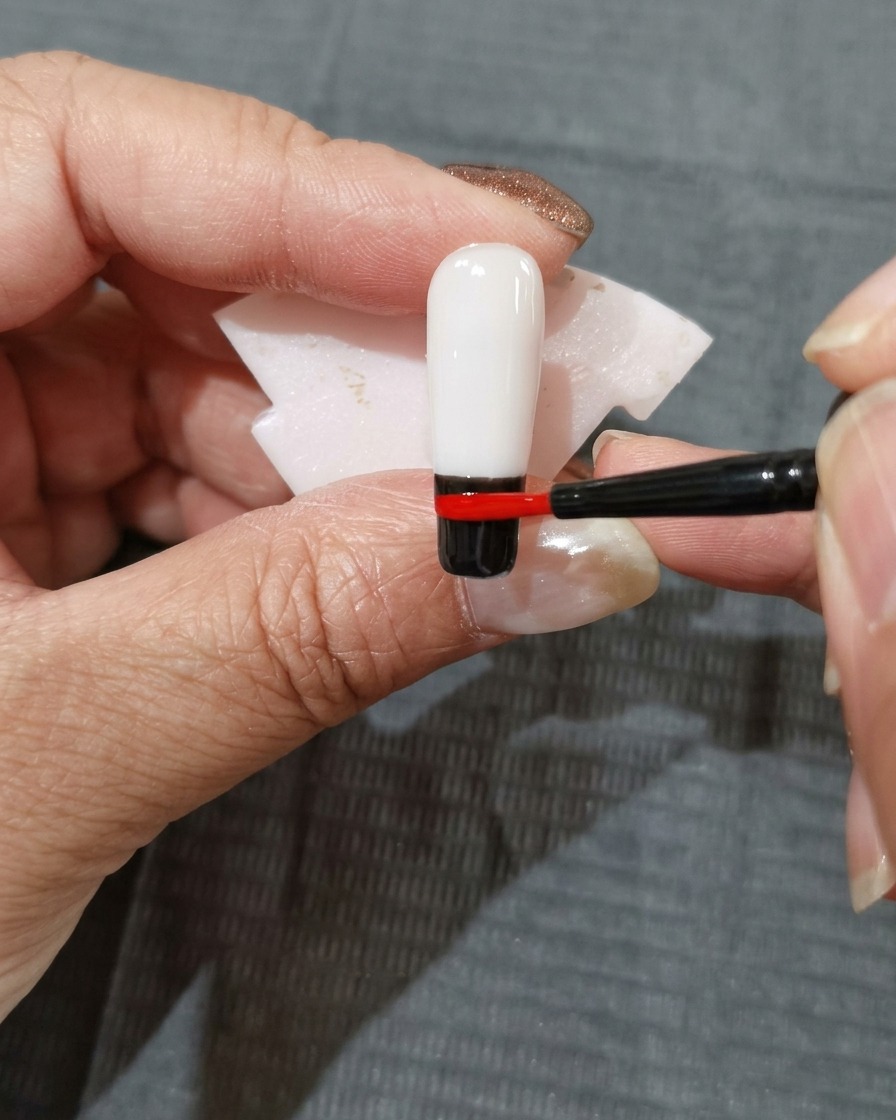 Ein Streifen orange-rotes Gel wird direkt über dem roten Farbbereich auf dem Nagel platziert.