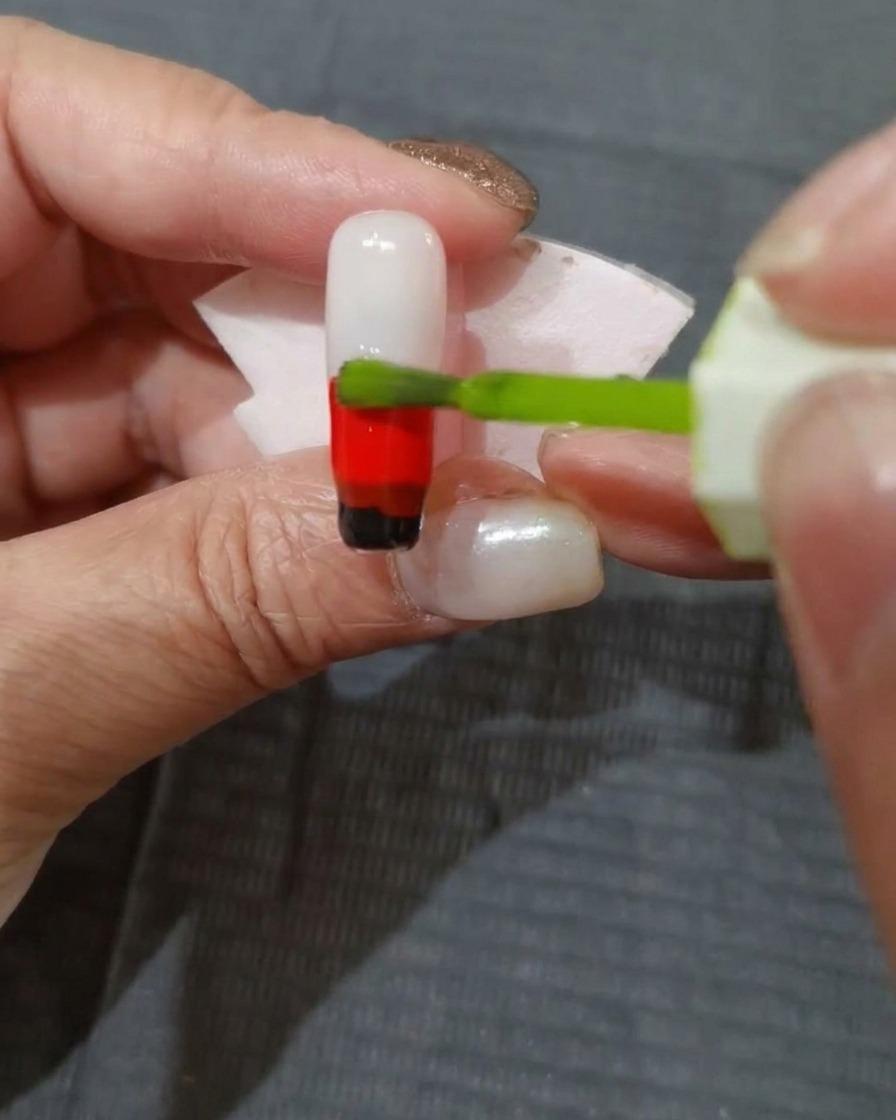 Eine Schicht gelb-grünes Gel wird auf den oberen Teil des Nagels aufgetragen.