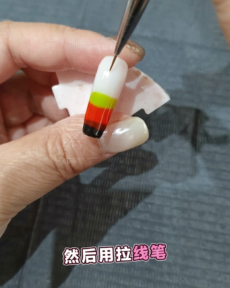 Ein feiner Nailart-Pinsel zieht durch mehrere Schichten feuchten, farbigen Gels, um ein Flammenmuster zu erzeugen.