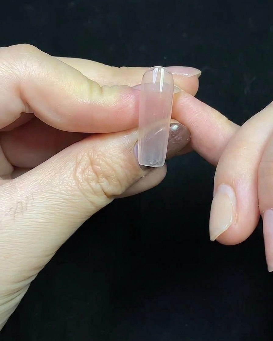 Nahaufnahme einer tiefroten Gel-French-Spitze, die auf eine transparente Nagelverlängerung gemalt wird.