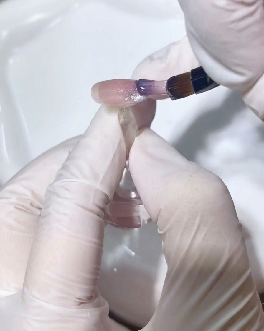 Ein feiner Detailpinsel verblendet vorsichtig das Cat-Eye-Gel, um einen nahtlosen Farbverlauf zu erzeugen.