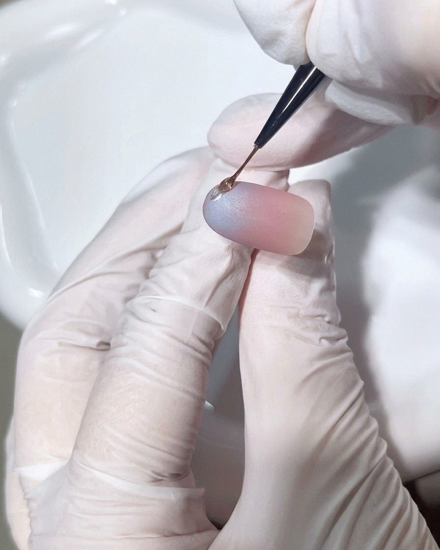 Nahaufnahme, wie ein Detailpinsel einen präzisen Tropfen klares Hard-Gel auf den Nagel aufträgt, um einen 3D-Akzent zu formen.