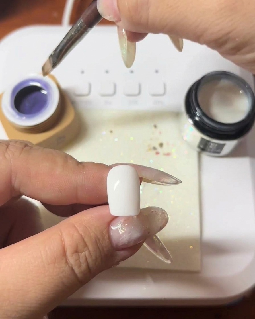Ein Pinsel trägt eine Schicht tiefviolettes Cat-Eye-Gel auf einen Nagel auf.