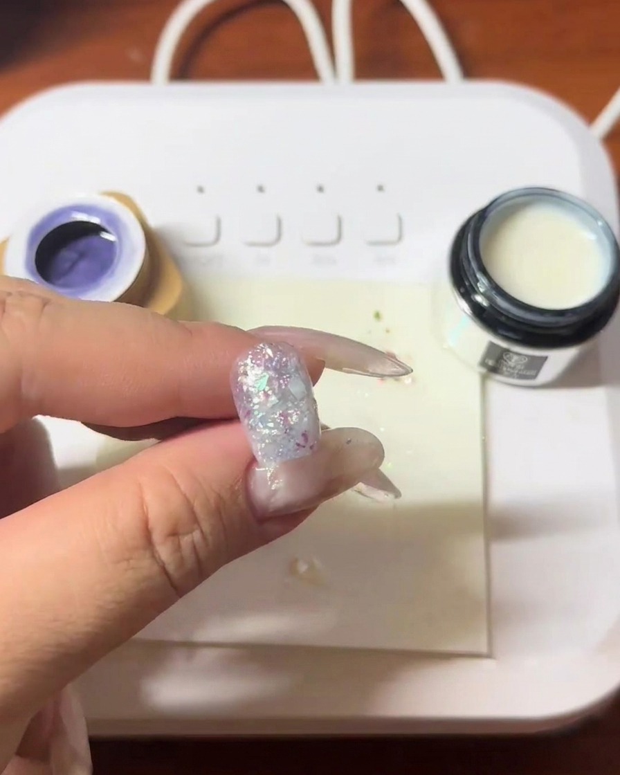 Ein Nagel mit eingebetteten Muschelfragmenten härtet unter einer LED-Lampe aus.