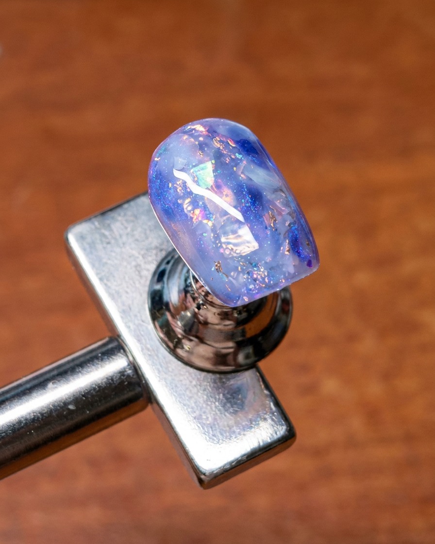 Ein Pinsel verblendet Base-Gel über die Ränder der eingebetteten Muscheln und Glitzer-Nailart für einen weichen, diffusen Look.