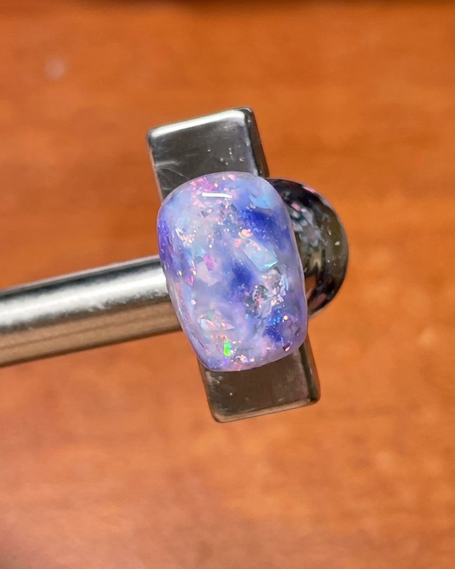 Ein Top-Coat-Pinsel trägt eine finale Versiegelungsschicht über der fertigen violetten Muschel- und Glitzernailart auf.