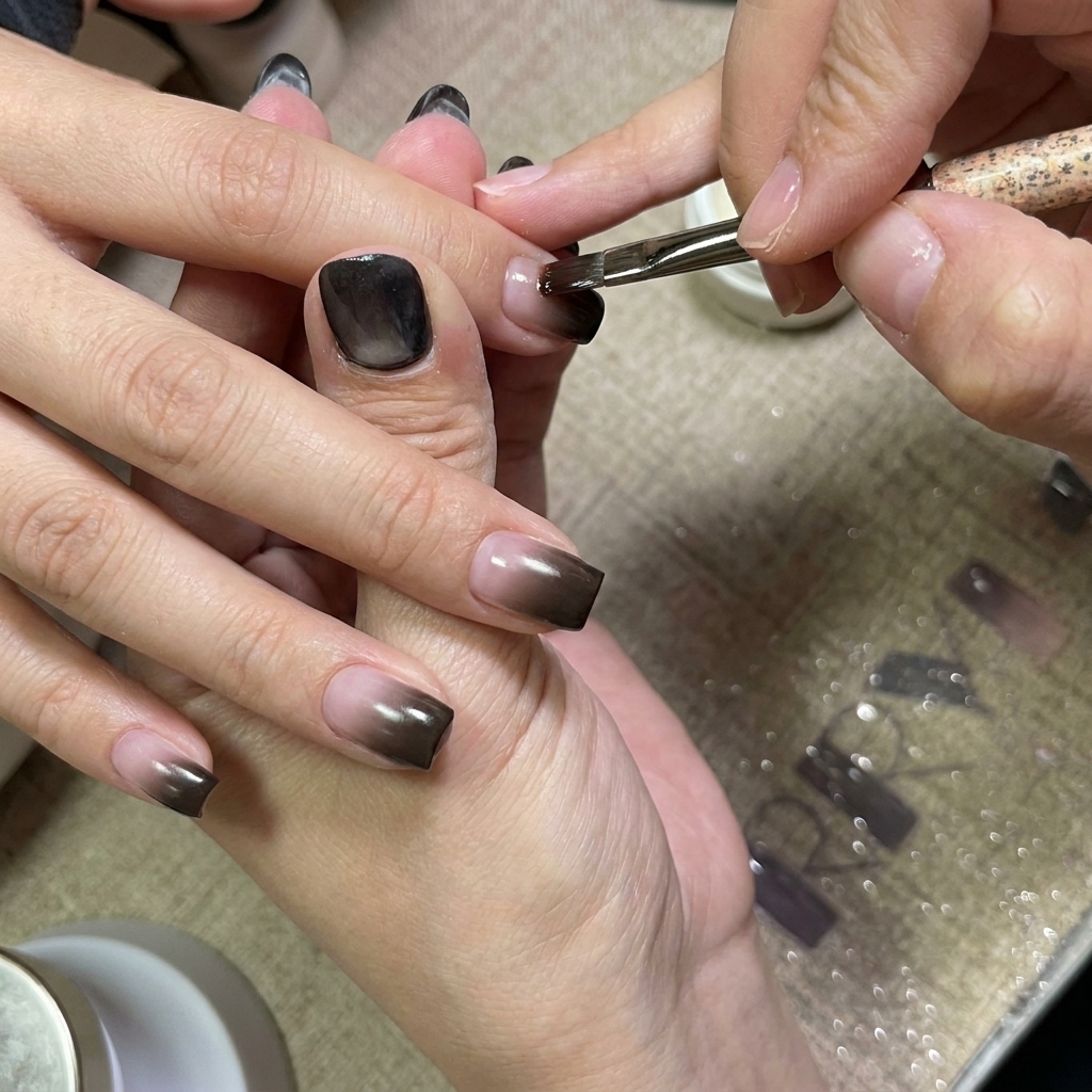 Ein Nagelpinsel trägt eine glatte Schicht klares Gel auf die Nägel mit Verlauf auf.