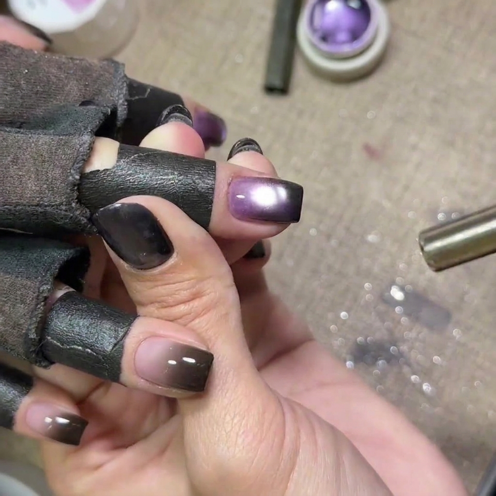 Nägel mit lila Cat-Eye-Gel härten unter einer UV-Lampe aus, das Licht ist sichtbar.