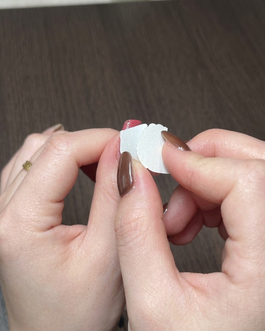 Nahaufnahme eines Make-up-Schwämmchens, das rotes Gel auf die freie Nagelkante tupft.