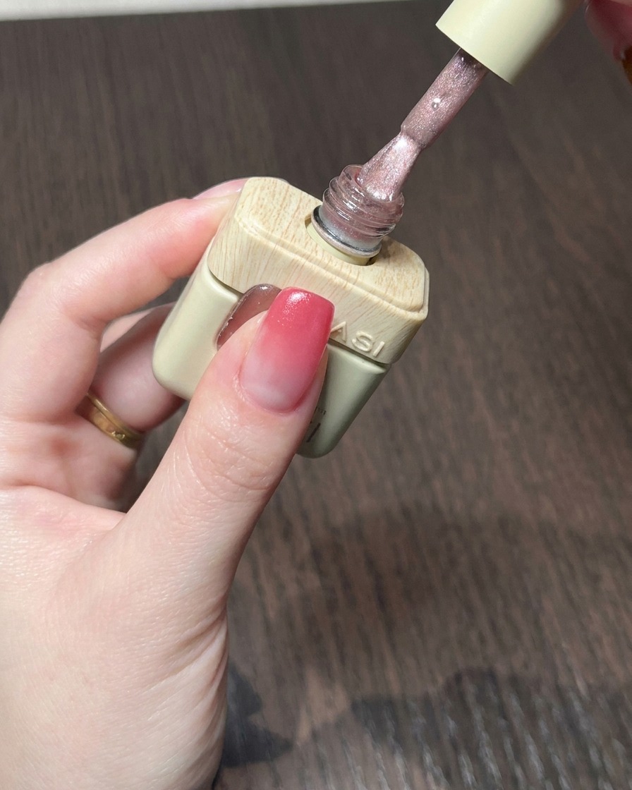 Ein Pinsel trägt ein schimmerndes, nudefarbenes Cat-Eye-Gel über der roten Gradient-Basis auf.