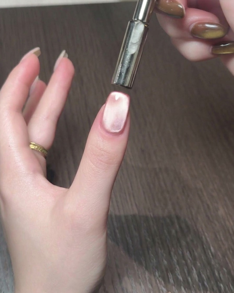 Ein magnetisches Werkzeug wird verwendet, um den Cat-Eye-Schimmer in ein leuchtendes Band auf dem Nagel zu lenken.