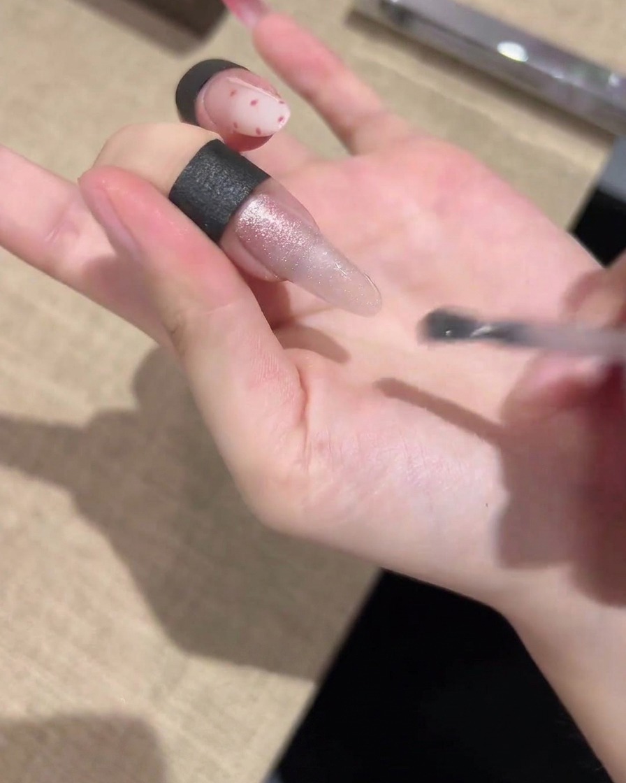 Ein Pinsel trägt ein schimmerndes Cat-Eye-Gel gleichmäßig über die gesamte Länge des Nagels auf.