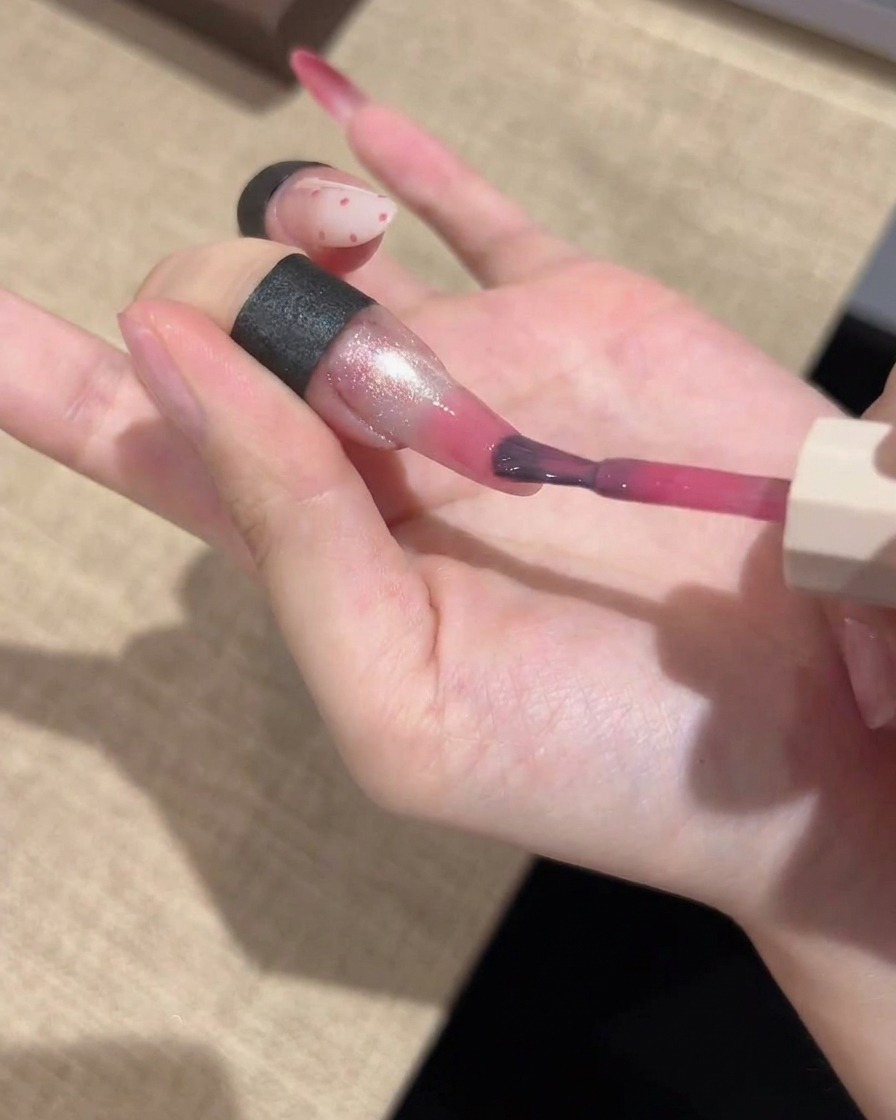 Ein feiner Detailpinsel trägt eine kräftige pinke Gel-Farbe auf die Nagelspitzen auf und verblendet diese für einen Gradient-Effekt.