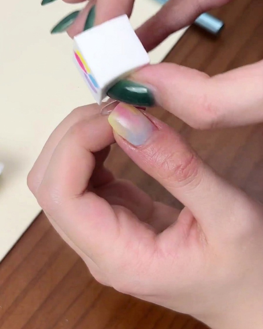 Ein Fingernagel in einer roten, kuppelförmigen UV/LED-Lampe während des Aushärtungsvorgangs.