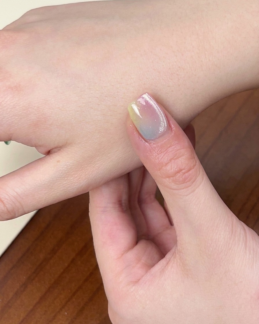 Nahaufnahme einer Hand mit der fertigen, bunten Gradient-Maniküre in einer UV/LED-Nagellampe.