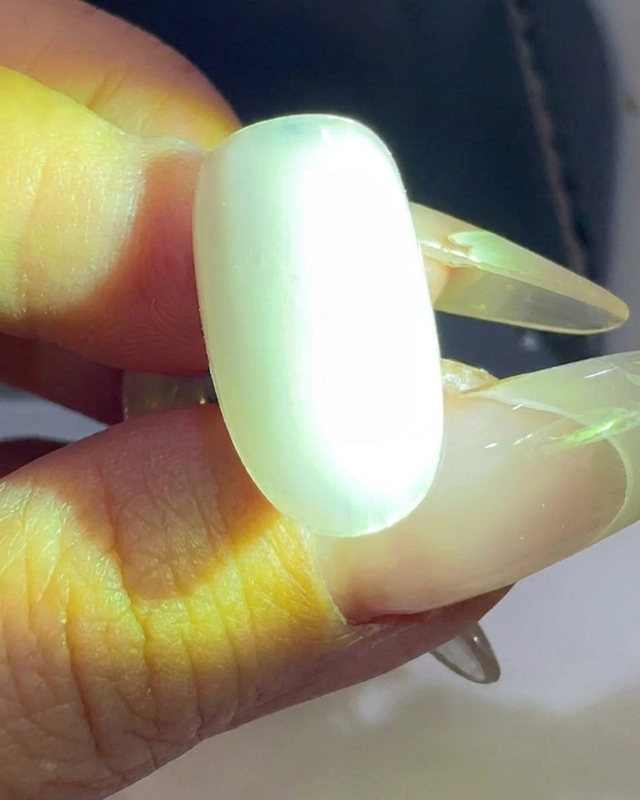 Ein transparenter Nageltip wird unter einer UV/LED-Lampe ausgehärtet.