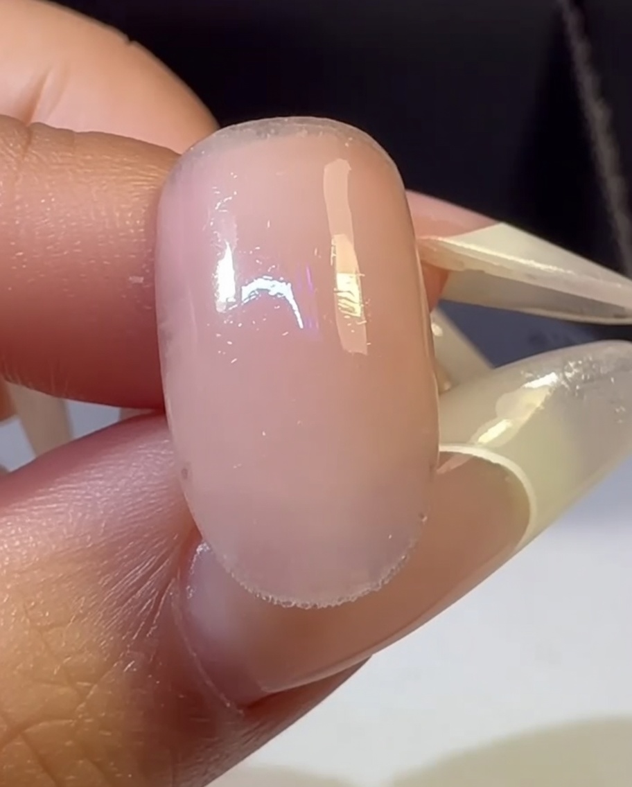 Eine Hand mit einem mehrfarbigen Ombré-Nagel wird in einer UV-Lampe ausgehärtet.