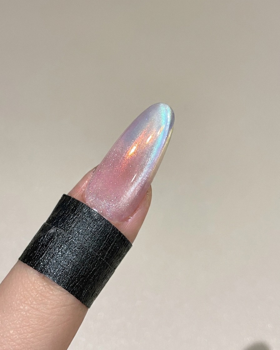 Ein Magnet wird seitlich an den Nagel gehalten, um die metallischen Partikel im feuchten Cat-Eye-Gel zu beeinflussen.