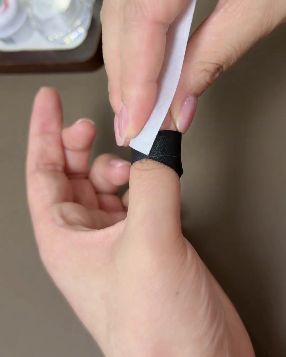 Ein fusselfreies Tuch wird verwendet, um die Oberfläche eines ausgehärteten Gelnagels zu säubern.