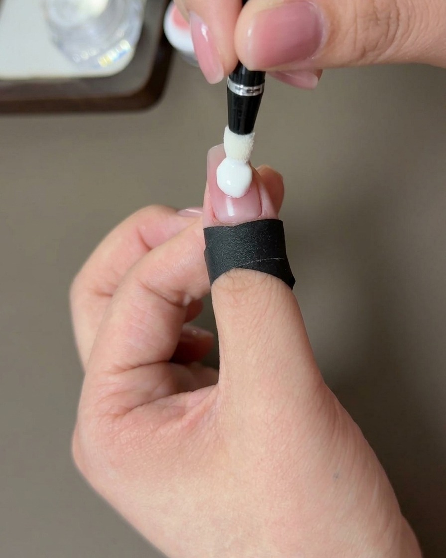 Nahaufnahme einer Hand, deren pfirsichfarbener Nagel unter einer UV-Lampe aushärtet.