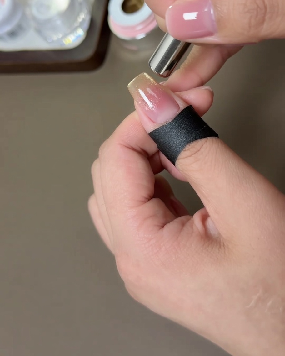 Ein zylindrischer Magnet wird seitlich an den Nagel gehalten, um die Goldpartikel zu bewegen.