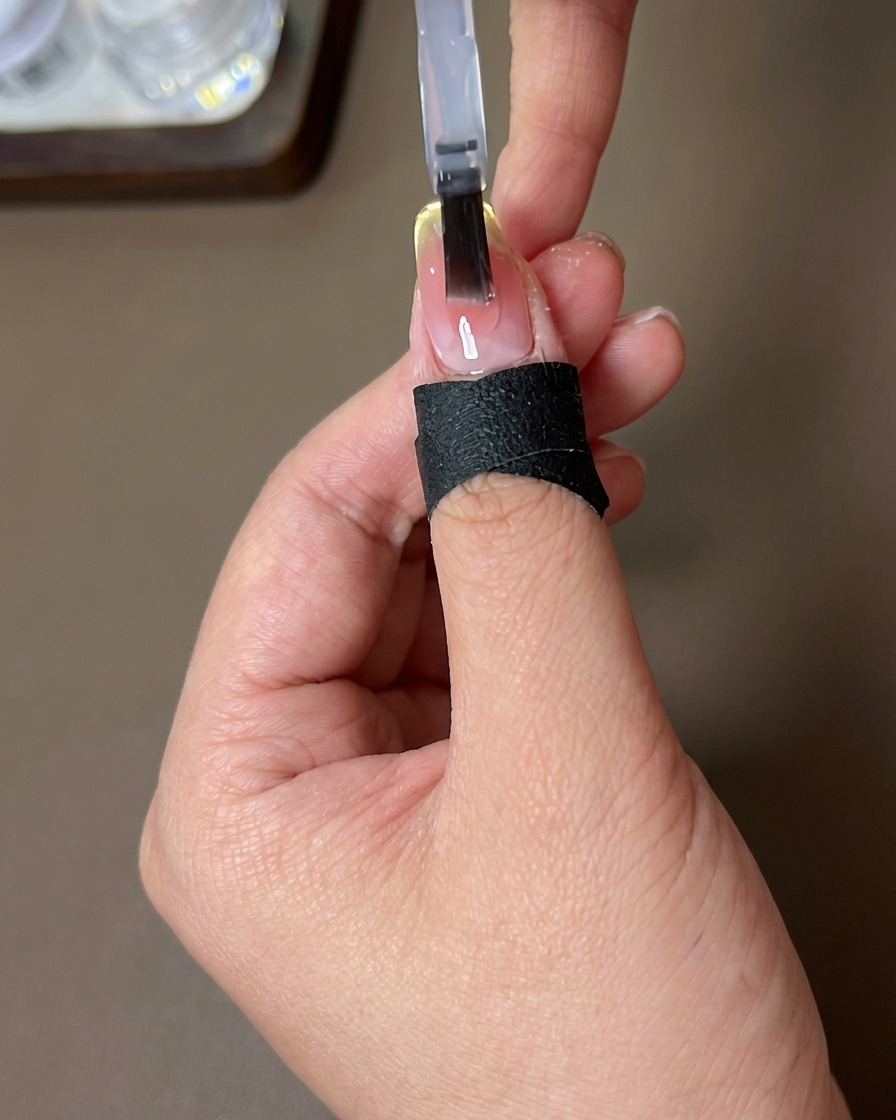 Ein Pinsel trägt einen glänzenden Top Coat auf das fertige Nageldesign auf.