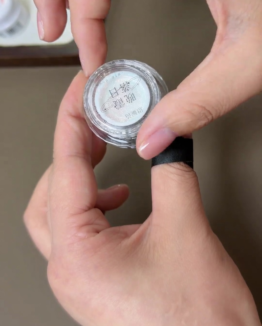Ein kleiner Behälter mit Aurora-Chrome-Puder und ein Applikator-Schwamm.