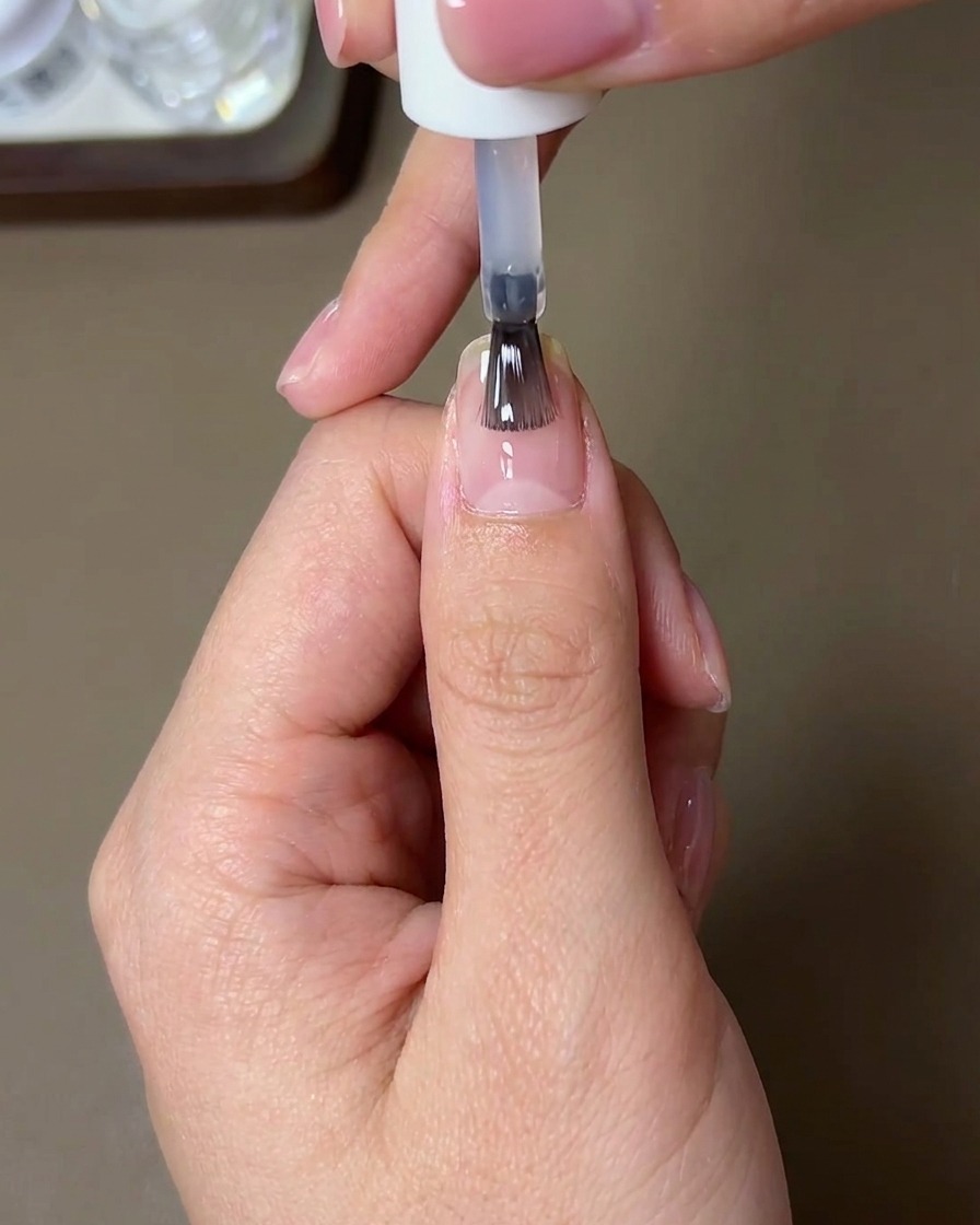 Ein Pinsel trägt einen verstärkenden Glanz-Top-Coat über den Chrome-Look auf.