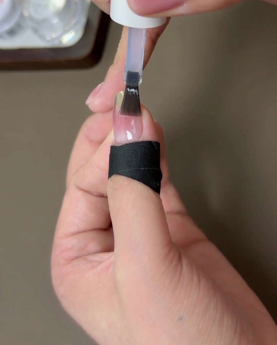 Der mit Top Coat versiegelte Nagel härtet unter der UV-Lampe aus.