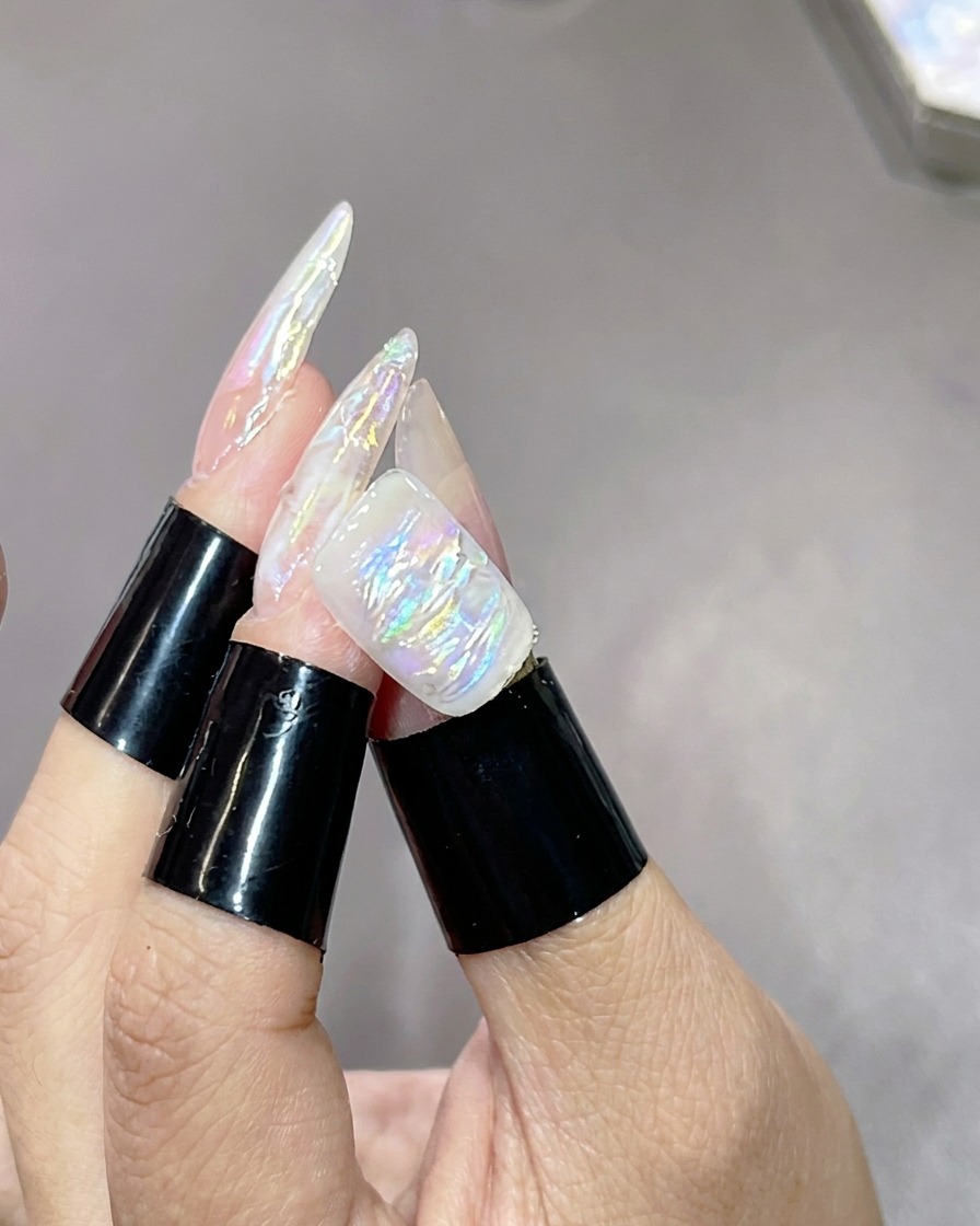 Eine Hand mit strukturierten, marmorierten Nägeln ruht in einer UV-Aushärtungslampe, um die Highlight-Schicht zu fixieren.