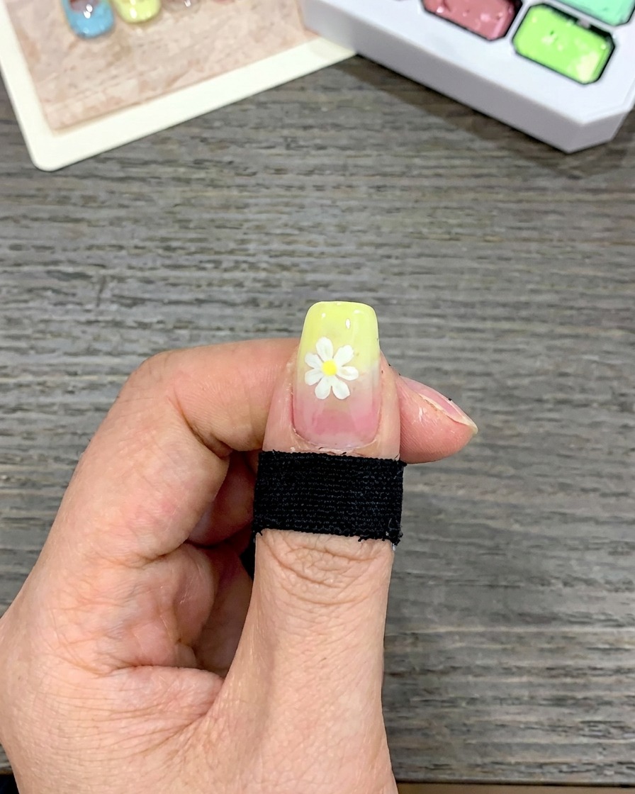Nahaufnahme eines Nagels, auf dessen Spitze mit einem eckigen Pinsel eine dicke Schicht gelbes Gel aufgetragen wird.