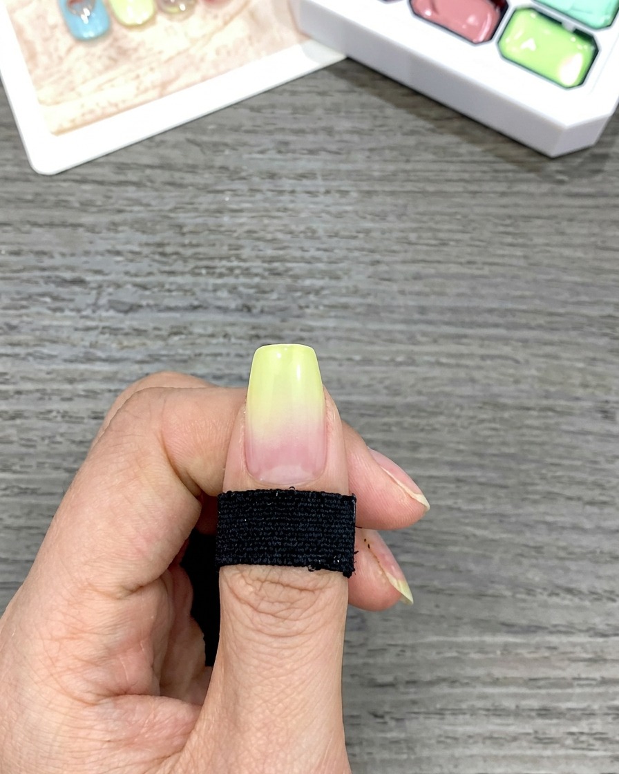 Nahaufnahme eines Fingernagels mit einem glatten, von Gelb zu Klar verlaufenden Ombré-Effekt.