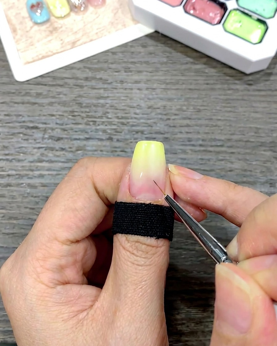 Ein feiner Detailpinsel setzt kleine weiße Punkte als Orientierungshilfe auf die Mitte eines Nagels mit gelbem Verlauf.