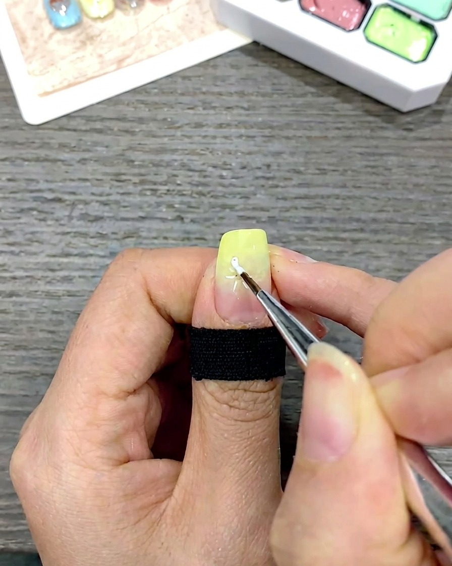 Ein feiner Liner-Pinsel zieht weiße Blütenblätter zum Zentrum des Nagels hin.