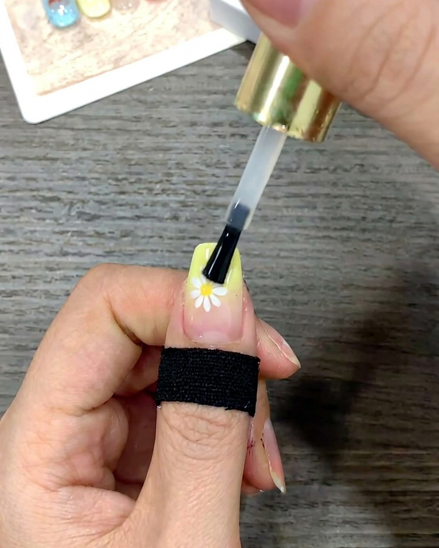 Nahaufnahme eines Nagelpinsels, der den Top Coat für eine glatte Oberfläche über den gesamten Nagel streicht.