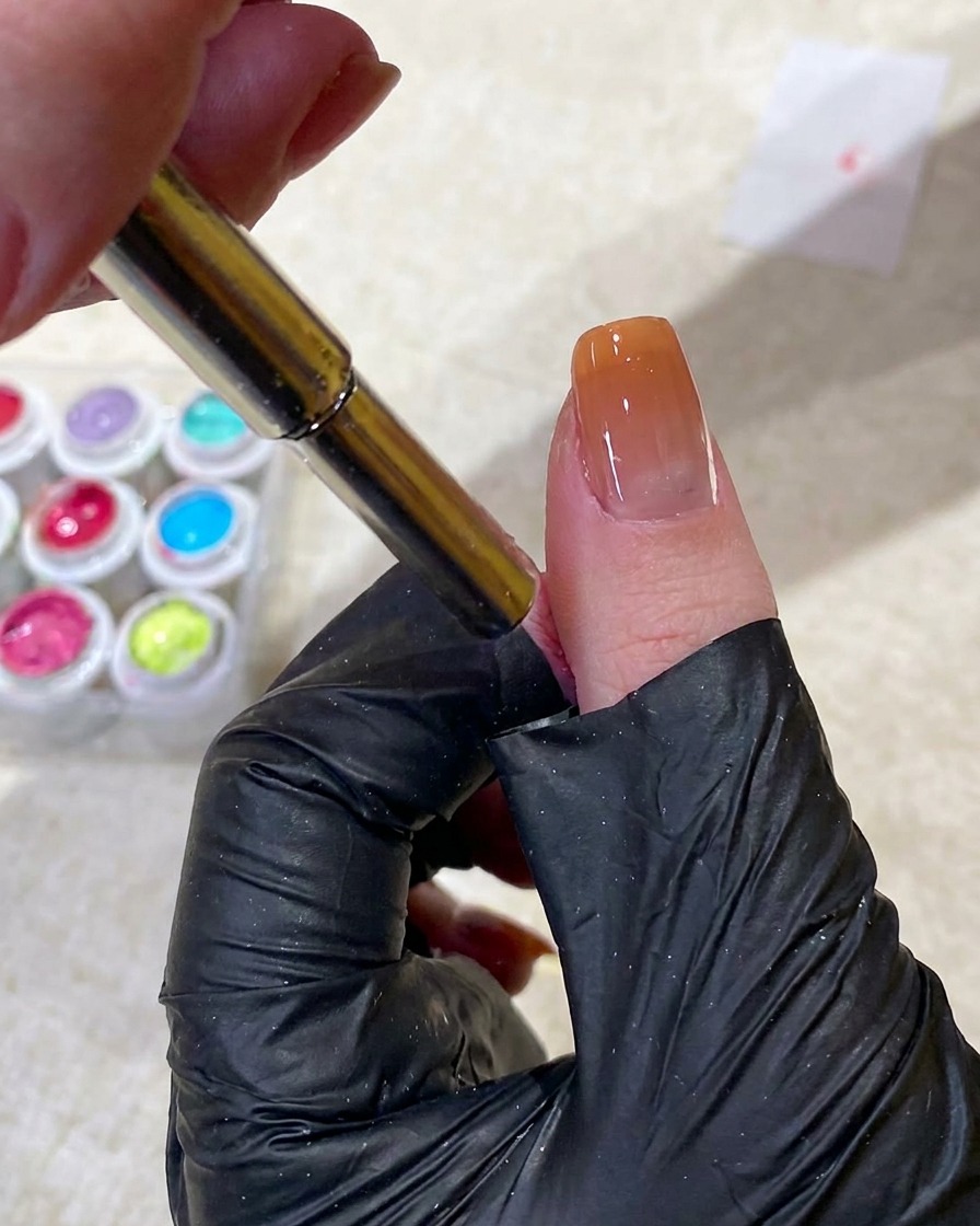 Ein Magnetwerkzeug wird verwendet, um Cat-Eye-Gel in eine kleine, kreisförmige Perlenform nahe der Nagelhaut zu ziehen.