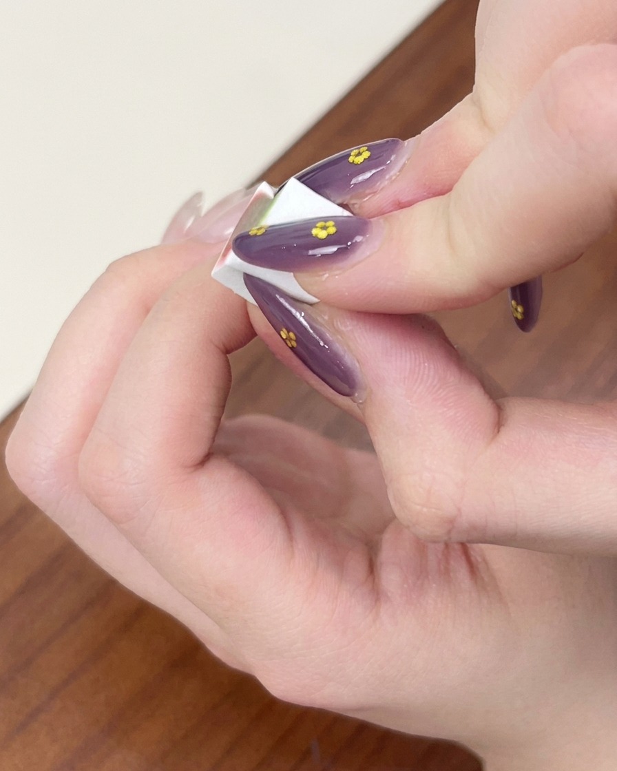 Finger halten ein kleines weißes Make-up-Schwämmchen, um das blaue Gel zu einem Ombré-Effekt auf dem Fingernagel zu verblenden.