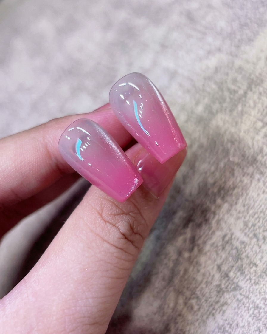 Ein Magnet-Tool wird nah an den Nagel gehalten, um die schimmernden Partikel zu einem konzentrierten Cat-Eye-Streifen zusammenzuziehen.