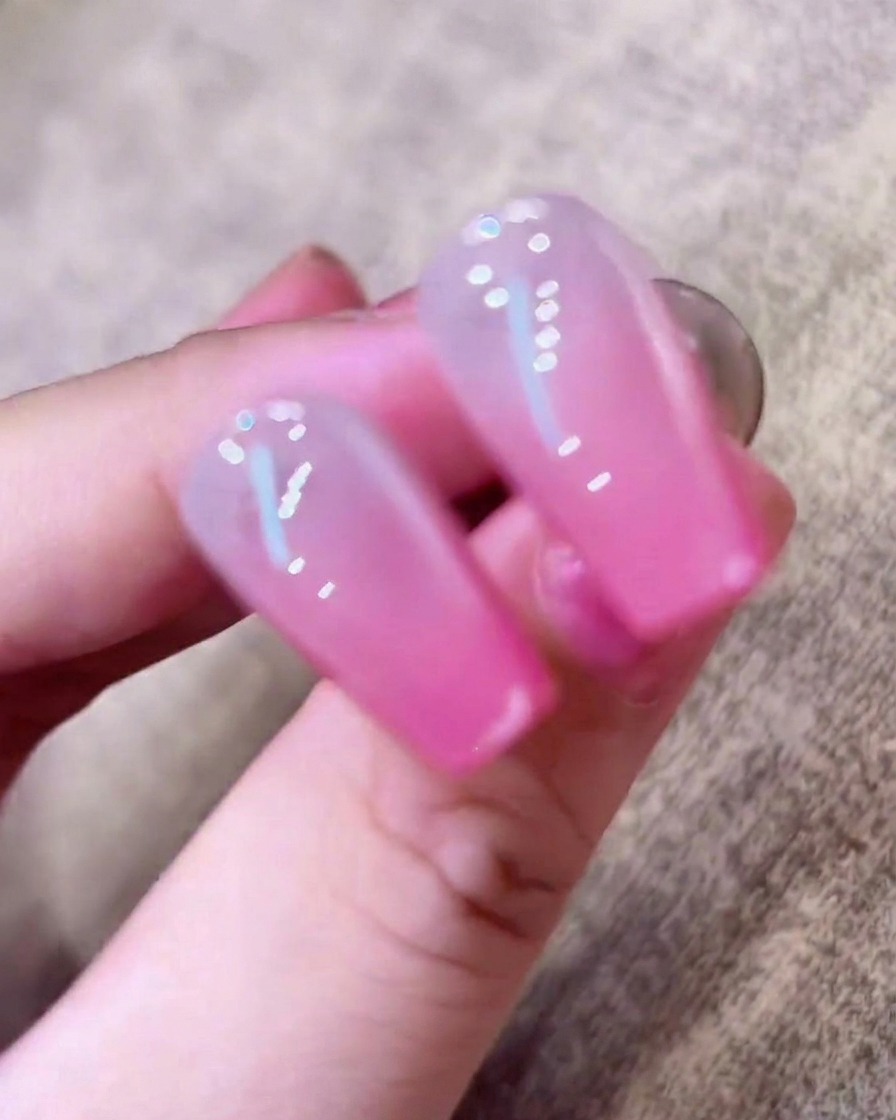 Eine Hand liegt in einer UV-Nagellampe, deren Licht die Finger beleuchtet.