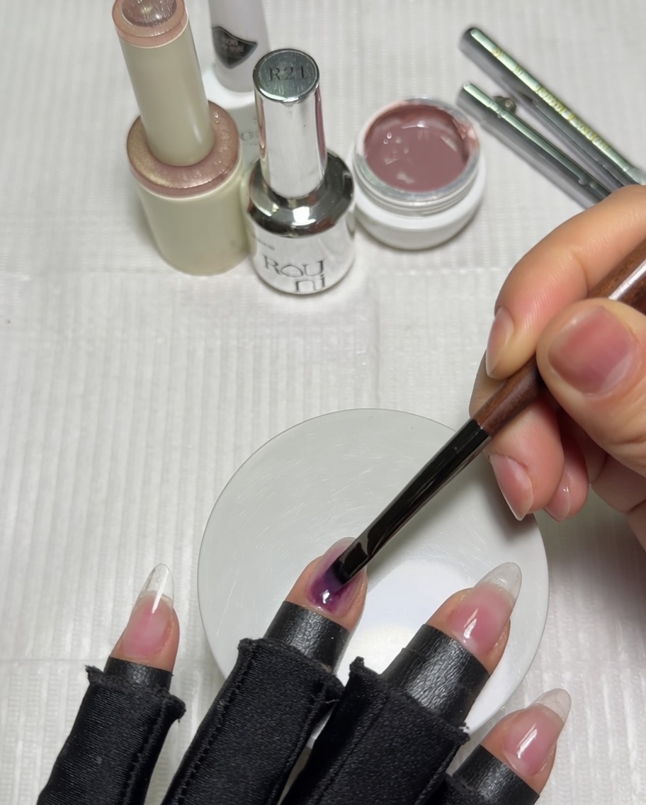 Eine Hand in einer violetten UV-Nagellampe mit Nude-farbener Gel-Basis auf den Nägeln.