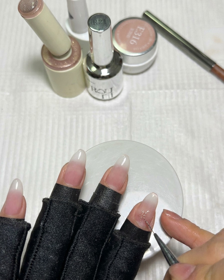 Ein feiner Liner-Pinsel füllt die Mitte eines rosa Gelsterns auf dem Nagel aus, um scharfe Spitzen zu erzeugen.
