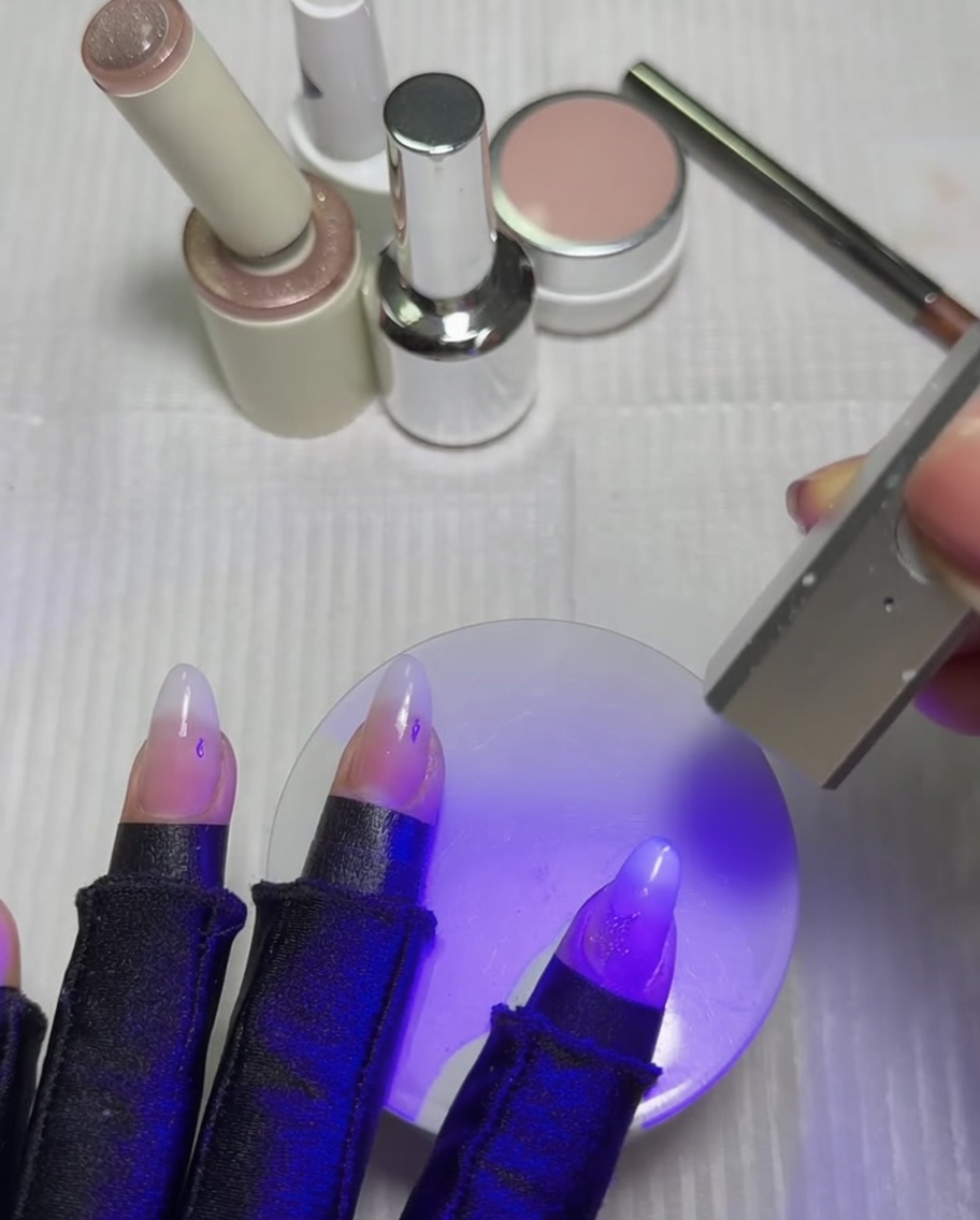 Nägel ruhen unter einer violetten UV- und LED-Lampe, um den frisch aktivierten Cat-Eye-Stern auszuhärten.