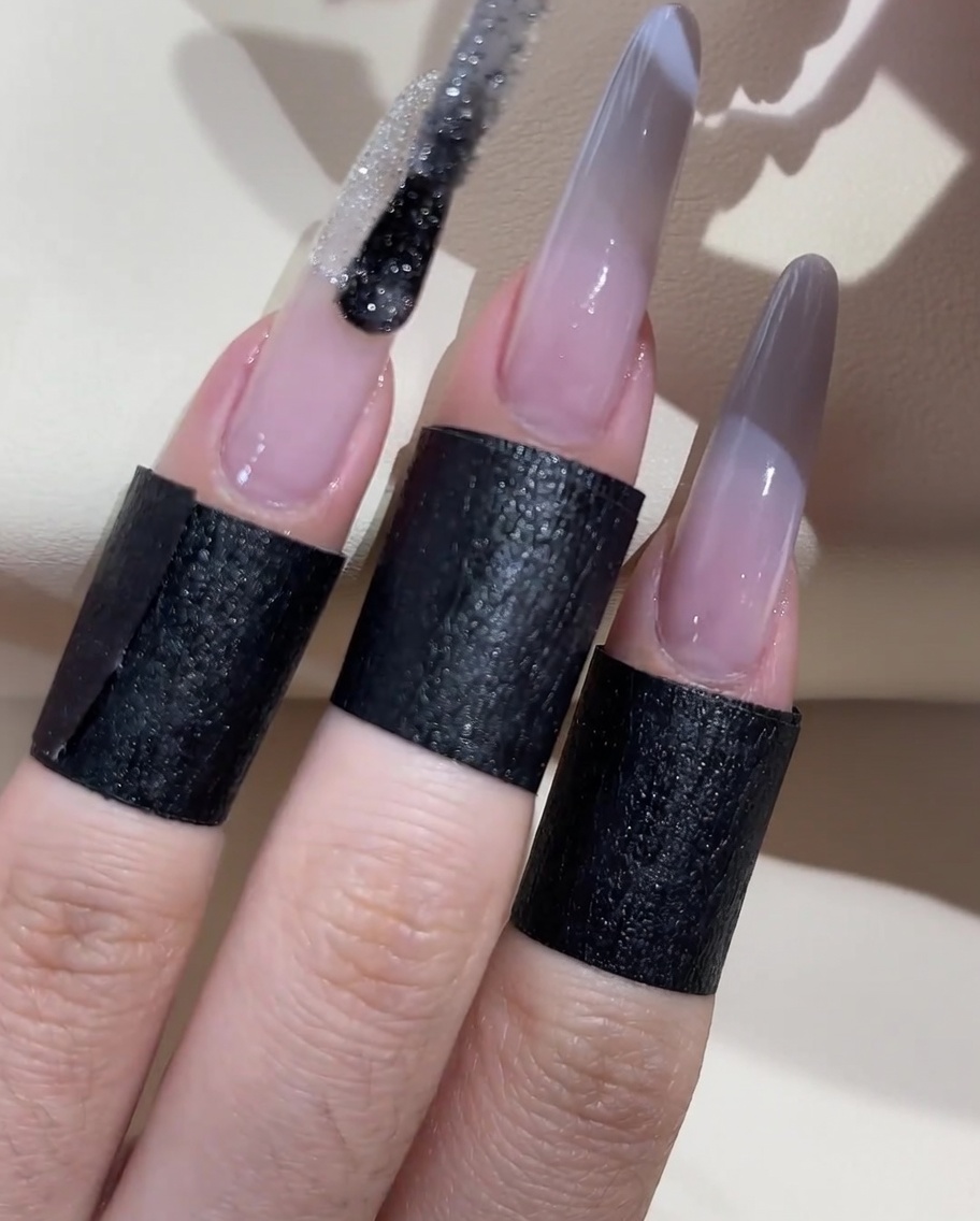 Ein Pinsel trägt eine Linie aus silbernem Glitzergel über die Mitte des Ombré-Übergangs auf.